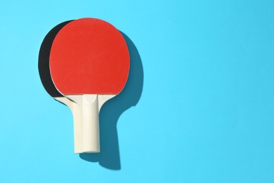 Photo of Ping pong rackets on blue background, top view. Space for text