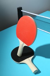 Photo of Ping pong rackets and net on light blue table