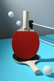 Photo of Ping pong rackets, balls and net on light blue table