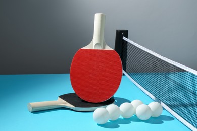 Photo of Ping pong rackets, balls and net on light blue table