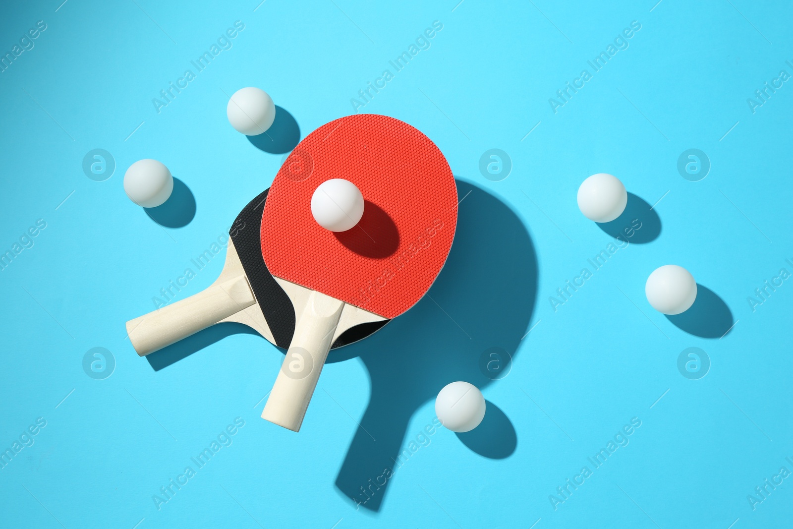 Ping pong rackets and balls on light blue background, flat lay Photo of Ping pong rackets and balls on light blue background, flat lay