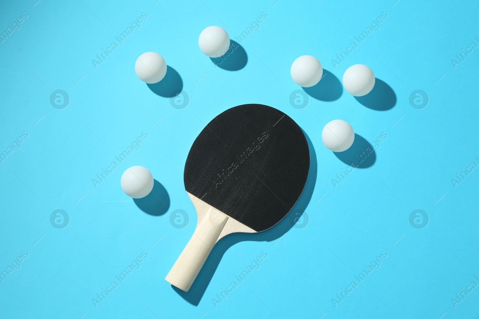 Ping pong racket and balls on light blue background, flat lay Photo of Ping pong racket and balls on light blue background, flat lay