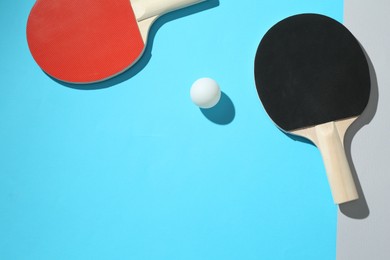 Photo of Ping pong rackets and ball on color background, top view. Space for text