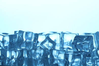 Photo of Many ice cubes on light background, closeup. Space for text