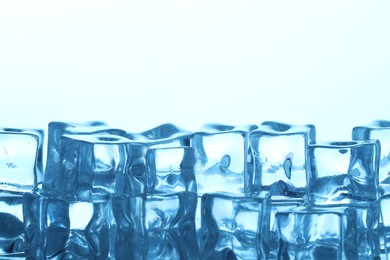 Photo of Many ice cubes on light background, closeup. Space for text