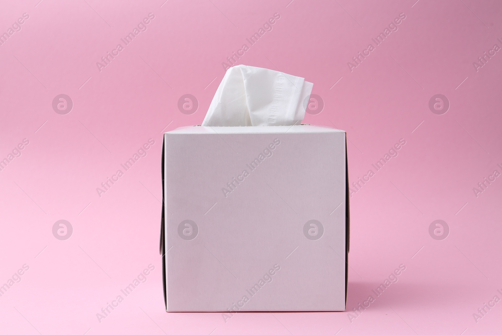 Box with paper handkerchiefs on pink background Photo of Box with paper handkerchiefs on pink background