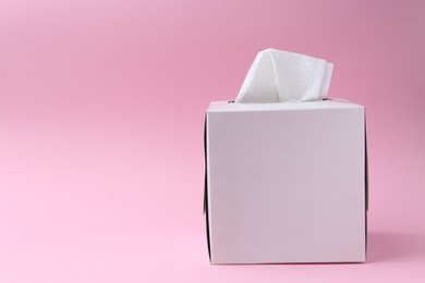 Photo of Box with paper handkerchiefs on pink background. Space for text