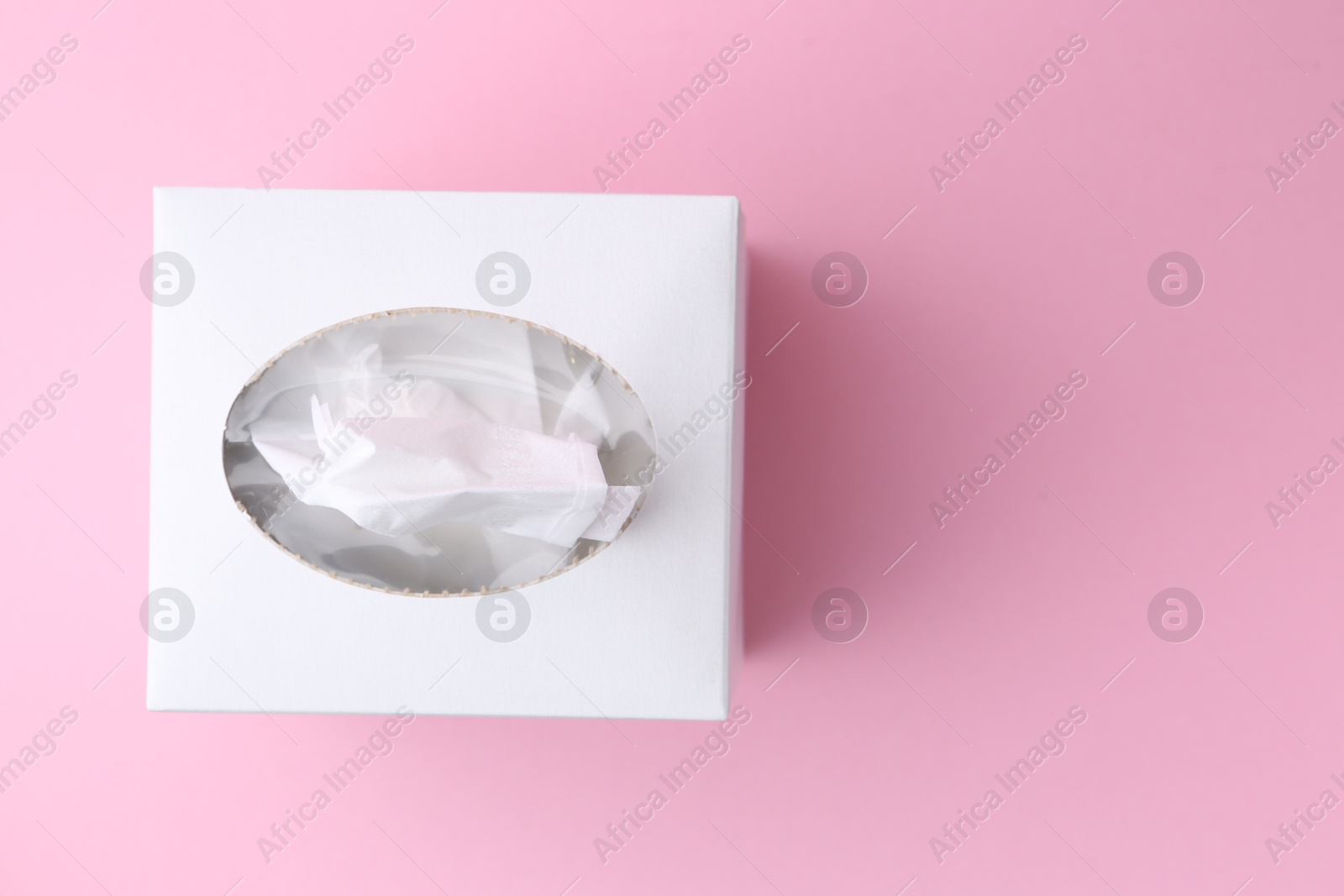 Box with paper handkerchiefs on pink background, top view. Space for text Photo of Box with paper handkerchiefs on pink background, top view. Space for text