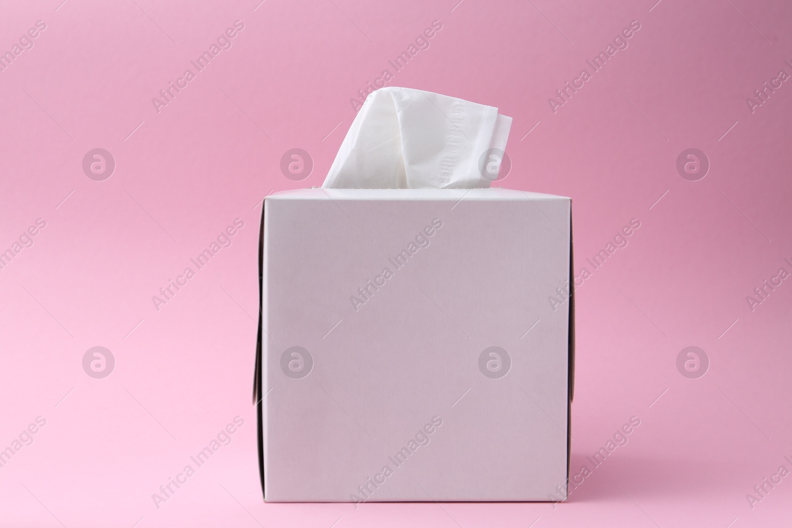 Box with paper handkerchiefs on pink background Photo of Box with paper handkerchiefs on pink background