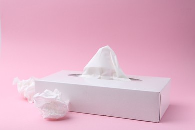 Photo of Box with paper handkerchiefs and crumpled tissues on pink background. Space for text