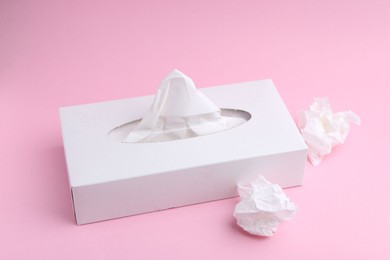 Photo of Box with paper handkerchiefs and crumpled tissues on pink background