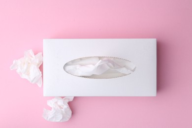 Photo of Box with paper handkerchiefs and crumpled tissues on pink background, flat lay