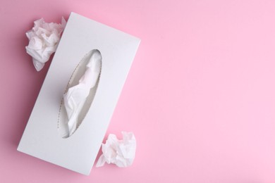Photo of Box with paper handkerchiefs and crumpled tissues on pink background, flat lay. Space for text