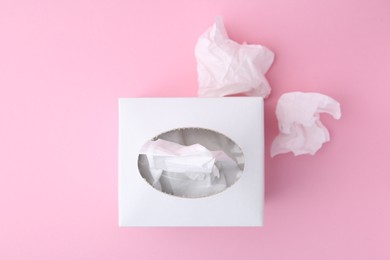 Photo of Box with paper handkerchiefs and crumpled tissues on pink background, flat lay