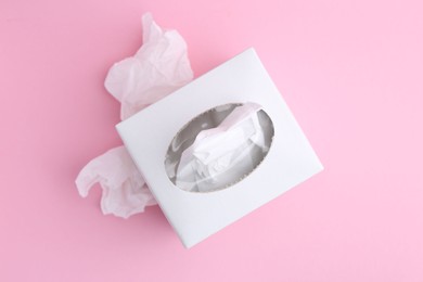 Photo of Box with paper handkerchiefs and crumpled tissues on pink background, flat lay