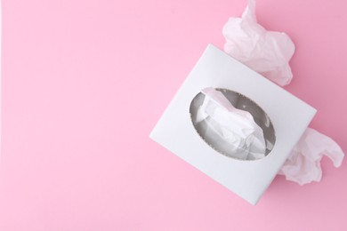 Photo of Box with paper handkerchiefs and crumpled tissues on pink background, flat lay. Space for text