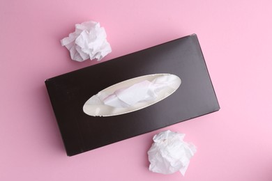 Photo of Box with paper handkerchiefs and crumpled tissues on pink background, flat lay