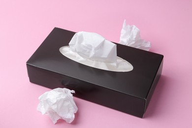 Photo of Box with paper handkerchiefs and crumpled tissues on pink background, closeup