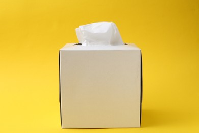 Photo of Box with paper handkerchiefs on yellow background
