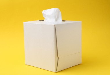 Photo of Box with paper handkerchiefs on yellow background