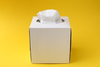 Photo of Box with paper handkerchiefs on yellow background