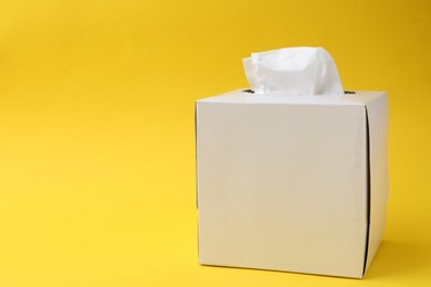 Photo of Box with paper handkerchiefs on yellow background. Space for text