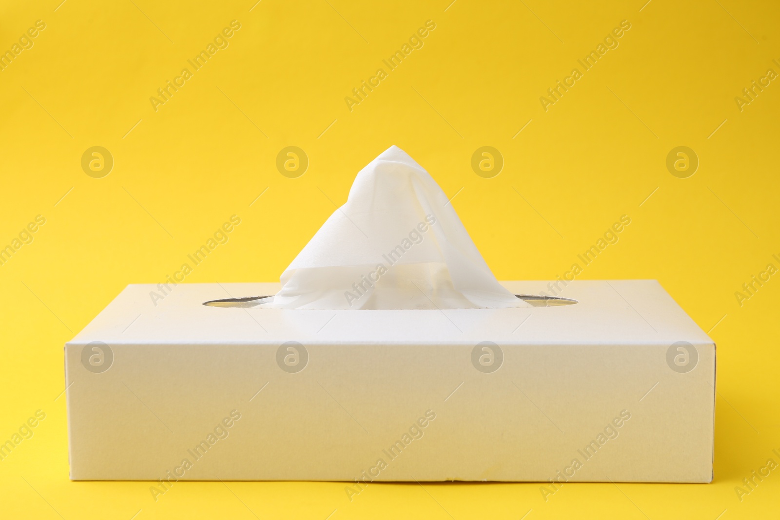 Box with paper handkerchiefs on yellow background. Space for text Photo of Box with paper handkerchiefs on yellow background. Space for text