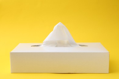 Photo of Box with paper handkerchiefs on yellow background. Space for text