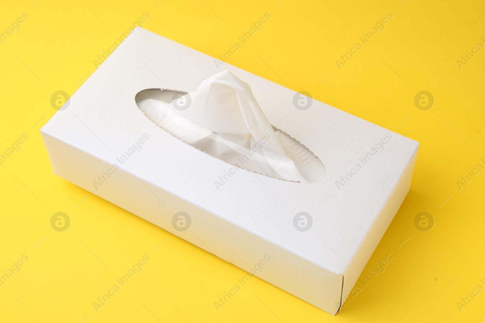 Box with paper handkerchiefs on yellow background, closeup Photo of Box with paper handkerchiefs on yellow background, closeup