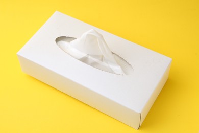 Photo of Box with paper handkerchiefs on yellow background, closeup