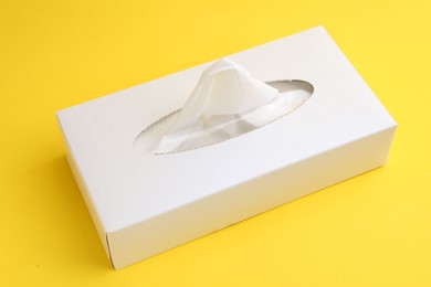 Photo of Box with paper handkerchiefs on yellow background, closeup