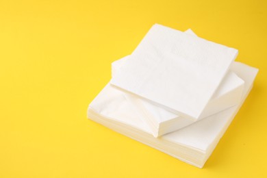 Photo of Stack of white handkerchiefs on yellow background, closeup. Space for text
