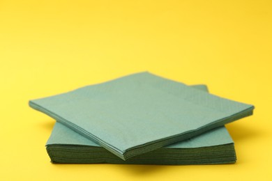 Photo of Stack of green handkerchiefs on yellow background, closeup. Space for text