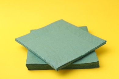 Photo of Stack of green handkerchiefs on yellow background, closeup