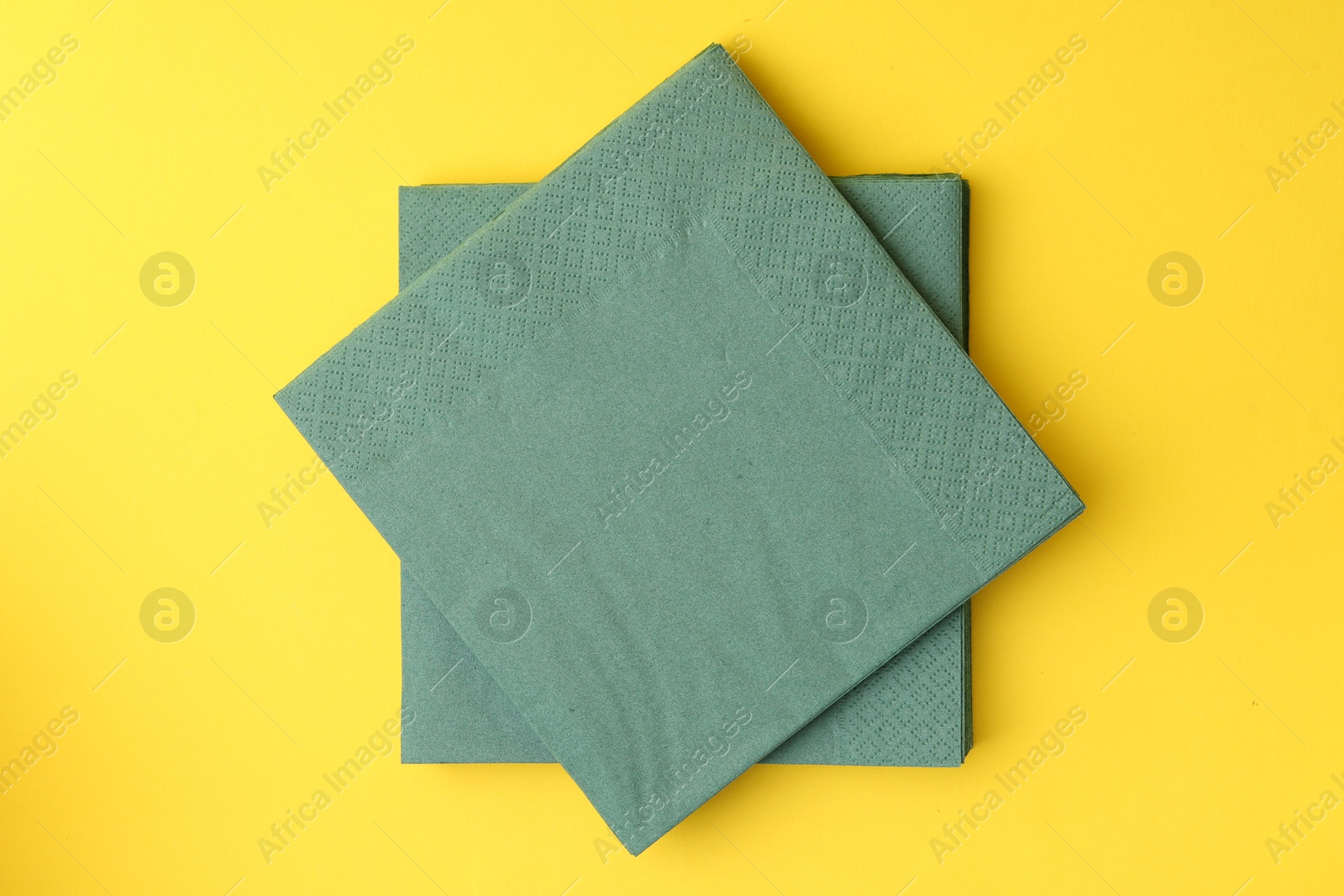 Stack of green handkerchiefs on yellow background, top view Photo of Stack of green handkerchiefs on yellow background, top view
