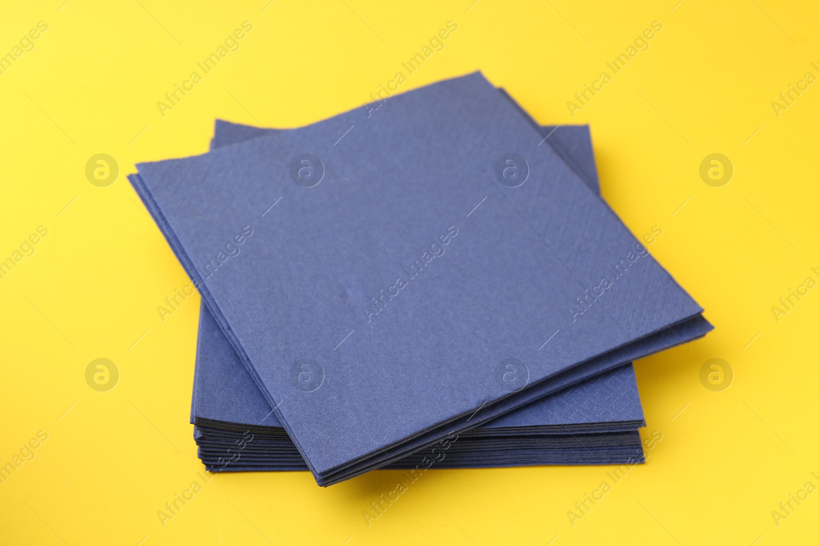 Stack of blue handkerchiefs on yellow background, closeup Photo of Stack of blue handkerchiefs on yellow background, closeup