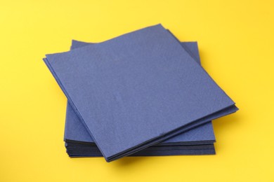 Photo of Stack of blue handkerchiefs on yellow background, closeup