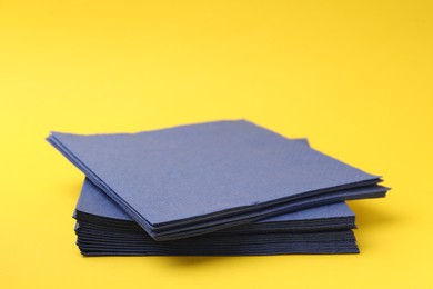 Photo of Stack of blue handkerchiefs on yellow background, closeup. Space for text