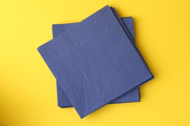 Photo of Stack of blue handkerchiefs on yellow background, top view