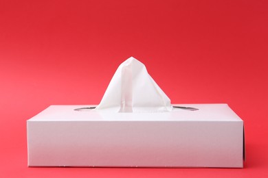 Photo of Box with paper handkerchiefs on red background, closeup