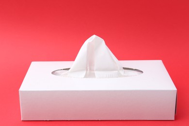 Photo of Box with paper handkerchiefs on red background, closeup