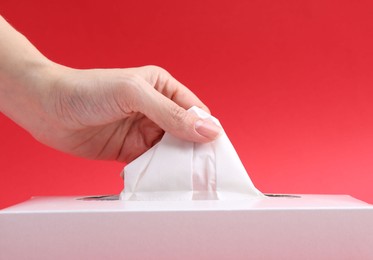Photo of Woman taking handkerchief out of box on red background, closeup