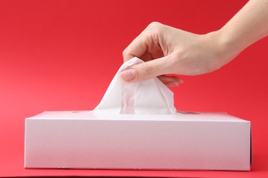 Photo of Woman taking handkerchief out of box on red background, closeup