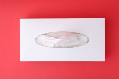 Photo of Box with paper handkerchiefs on red background, top view