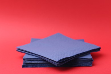 Photo of Stack of blue handkerchiefs on red background, closeup. Space for text