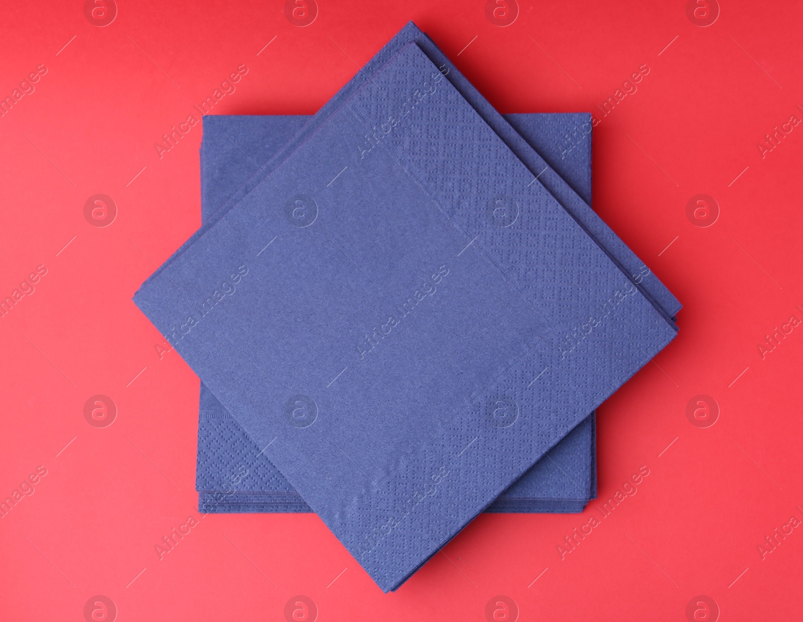 Stack of blue handkerchiefs on red background, top view Photo of Stack of blue handkerchiefs on red background, top view