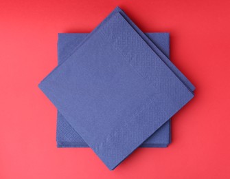 Photo of Stack of blue handkerchiefs on red background, top view
