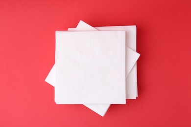 Photo of Stack of white handkerchiefs on red background, top view