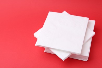 Photo of Stack of white handkerchiefs on red background, closeup. Space for text