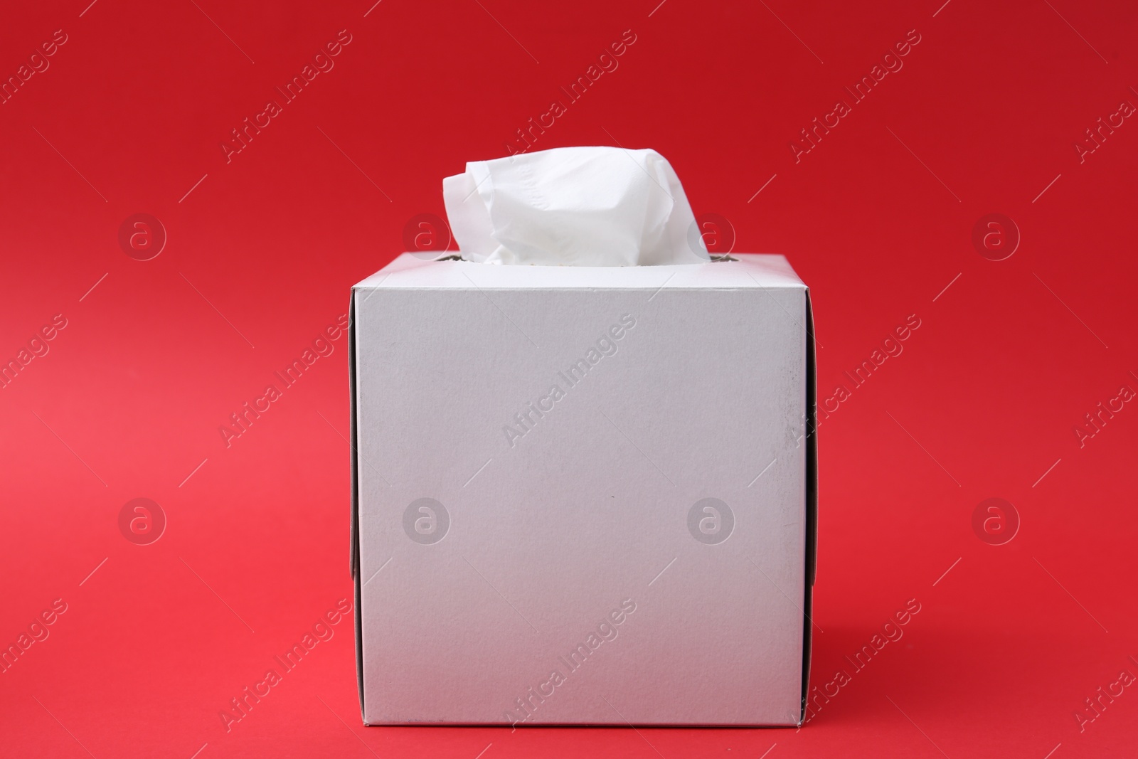 Box with paper handkerchiefs on red background Photo of Box with paper handkerchiefs on red background